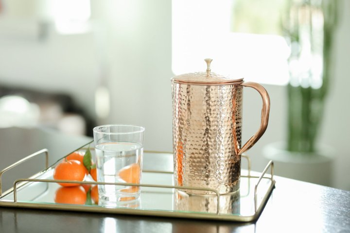 tray with a Shantiva copper pitcher and a glass of water and orange