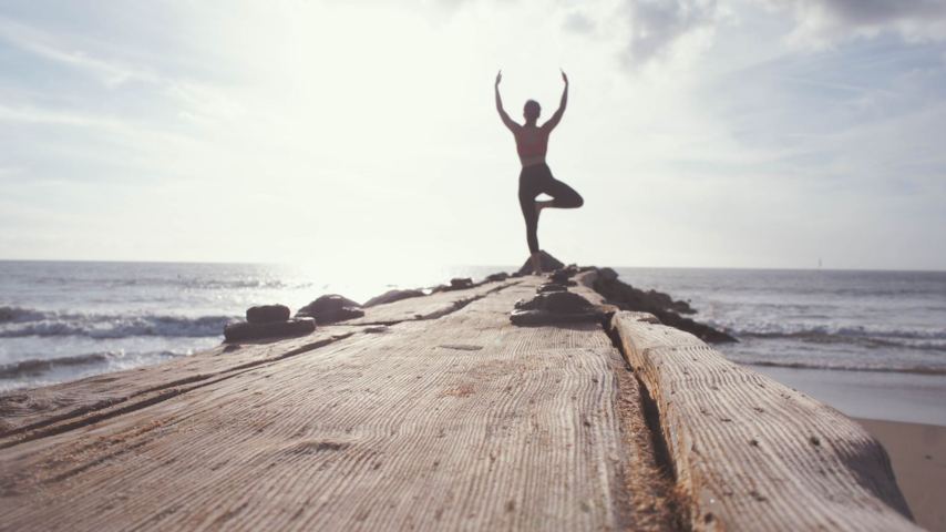 silhouette of a person doing a yoga pose on an edge of walkboard